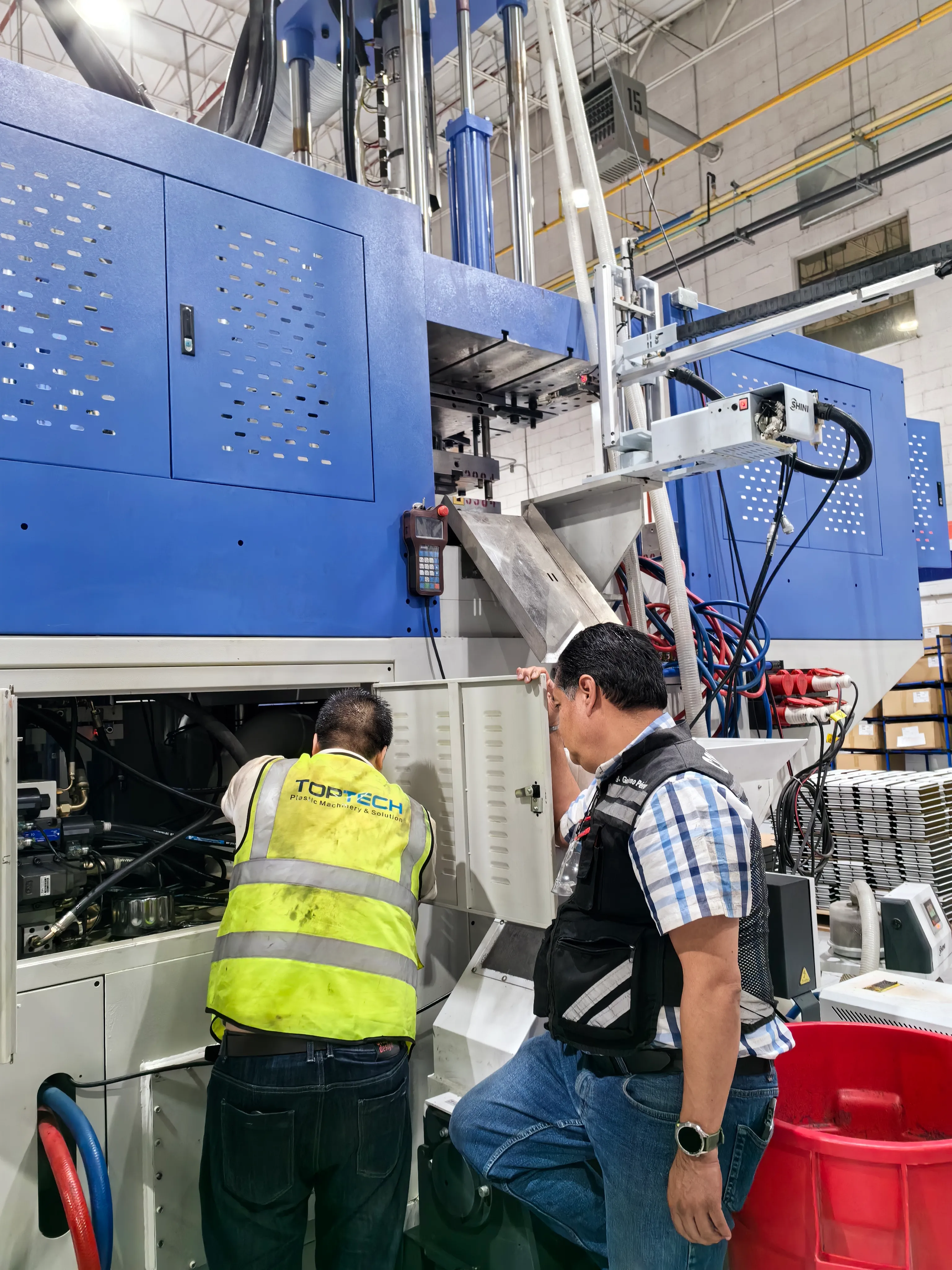 Deboge service engineer commissioning a vertical injection molding machine at a customer factory