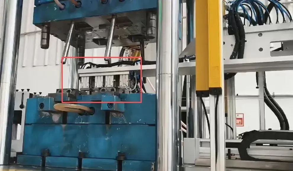Robotic handling unit positioned between the open mold halves of the DA-600DC